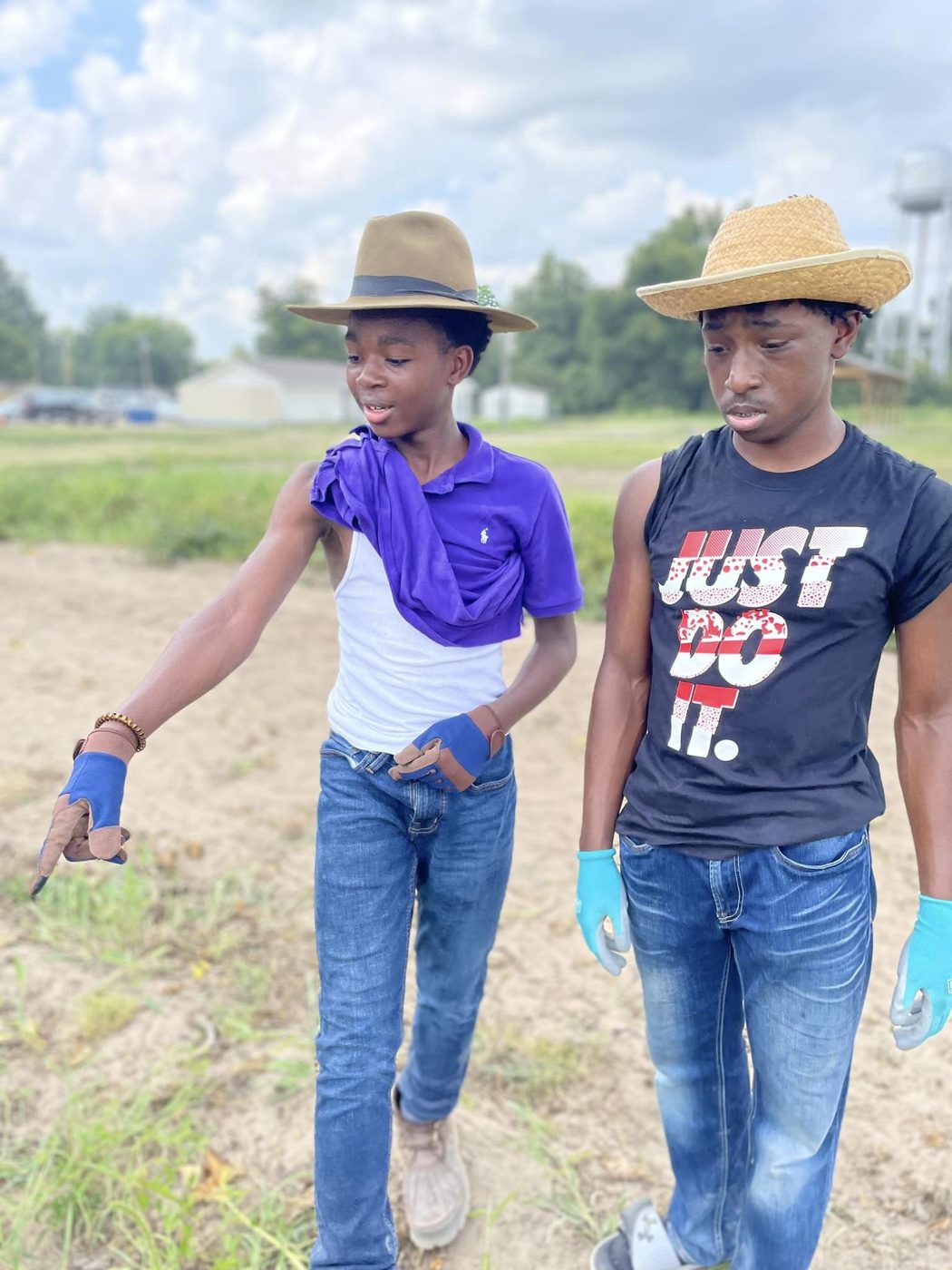 Two young men in straw hats walking through the farm